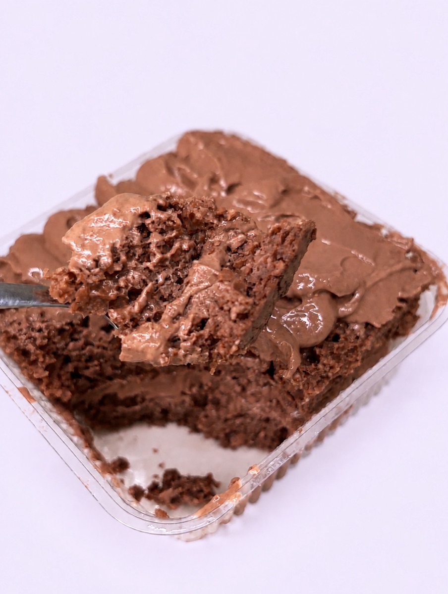 Bolo de chocolate com cobertura cremosa, com um pedaço no garfo