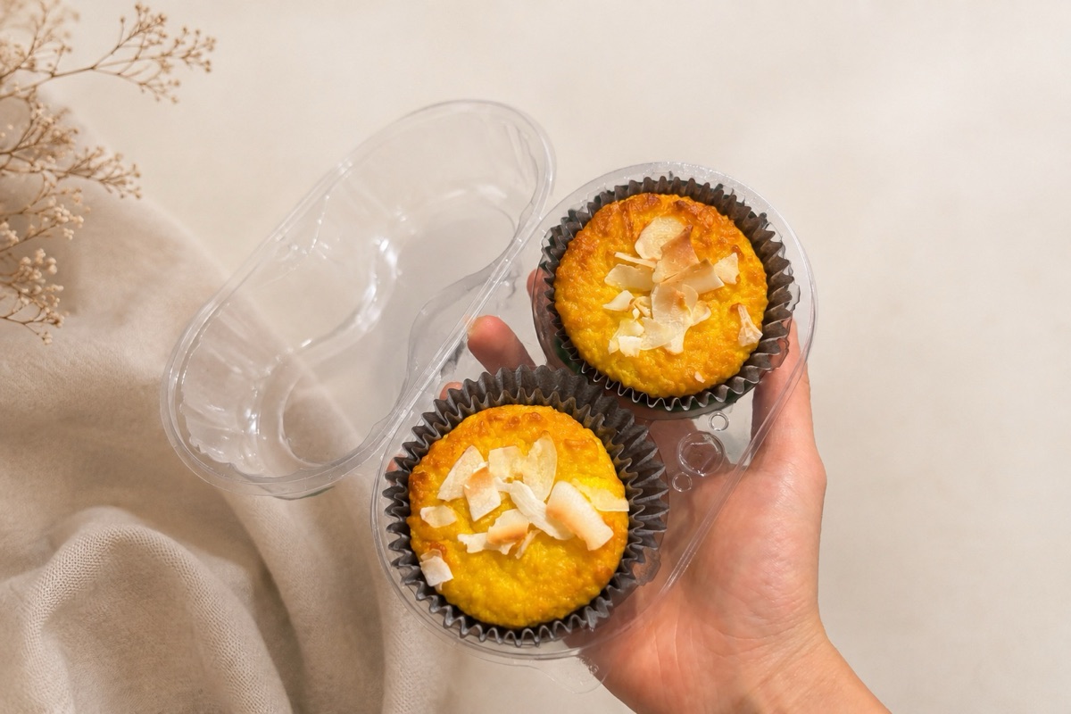 Dois muffins de abóbora com lascas de coco, na embalagem