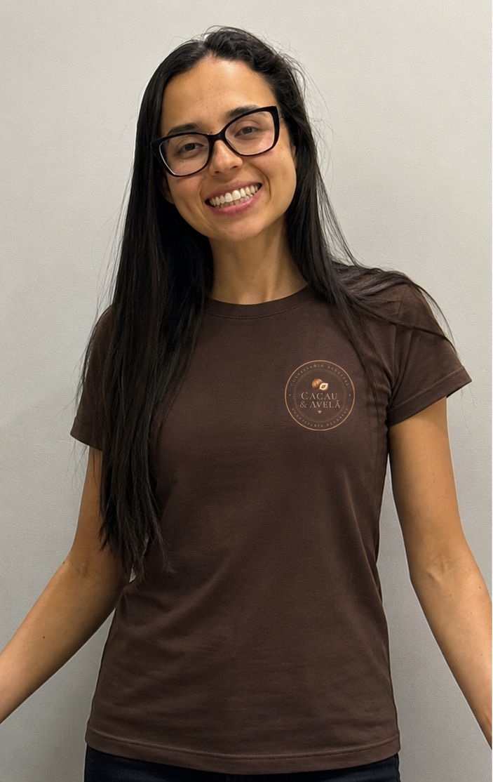 Gabi sorrindo, de camiseta marrom com o logo da Cacau & Avelã
